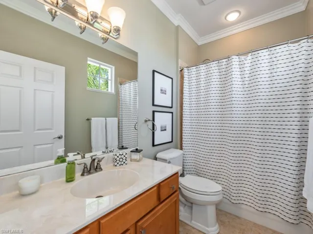 Bathroom with an inviting chandelier, tile patterned floors, toilet, vanity, and ornamental molding