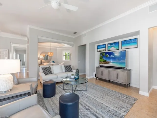 Living room with ceiling fan, ornamental molding, and light tile patterned floors