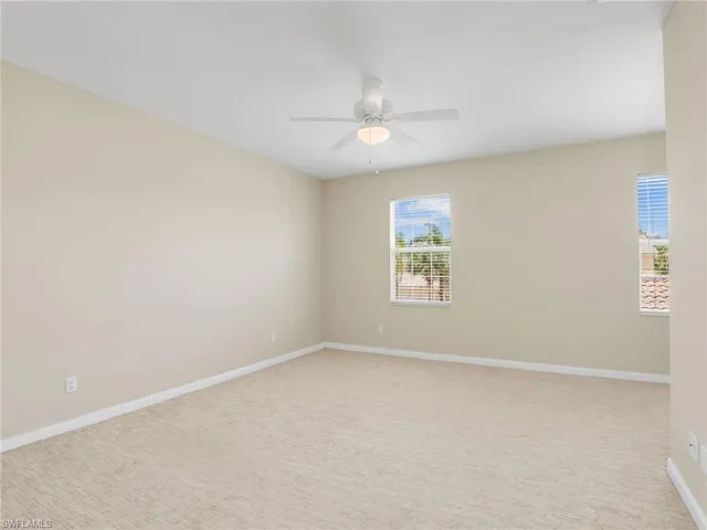 Carpeted spare room featuring a ceiling fan and baseboards