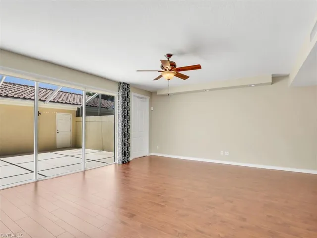 Unfurnished bedroom featuring wood finished floors, baseboards, access to outside, and a ceiling fan