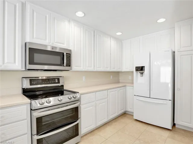 Kitchen featuring appliances with stainless steel finishes, light countertops, white cabinets, light tile patterned flooring, and recessed lighting