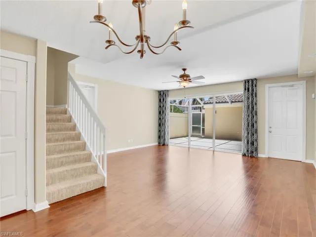 Unfurnished living room with a ceiling fan, wood finished floors, and stairs
