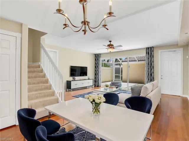 Living room with a chandelier, stairway, a ceiling fan, and wood finished floors