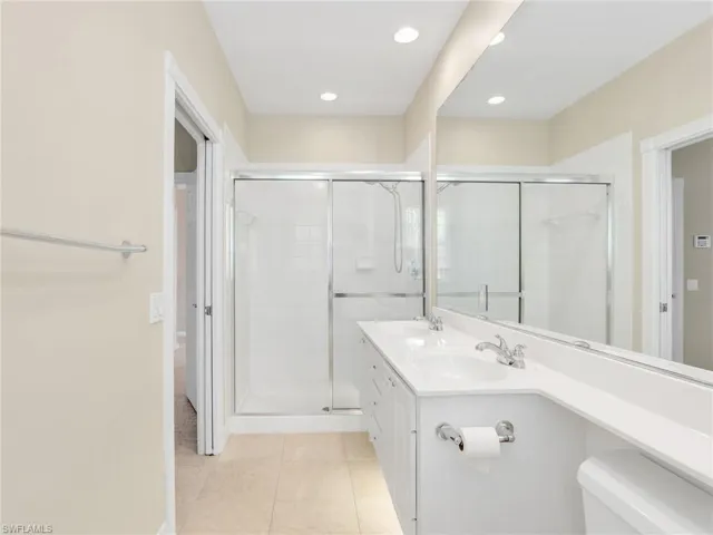 Full bathroom with tile patterned flooring, toilet, a stall shower, recessed lighting, and double vanity