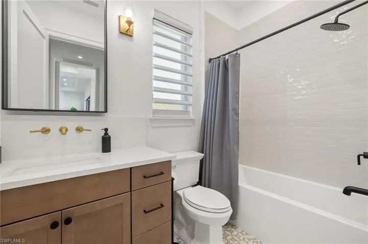 Bathroom featuring vanity, toilet, plenty of natural light, and shower / bathtub combination with curtain