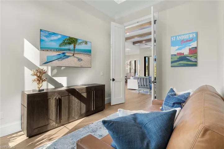 Living area featuring wood finished floors, crown molding, and baseboards
