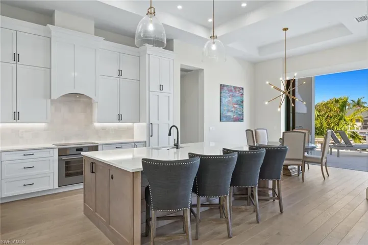Kitchen featuring oven, a sink, light wood finished floors, an island with sink, and recessed lighting