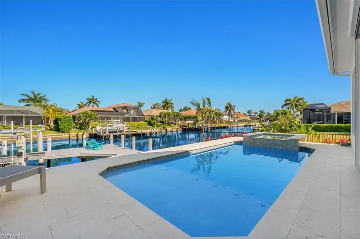 View of pool with a pool with connected hot tub, a water view, and a dock