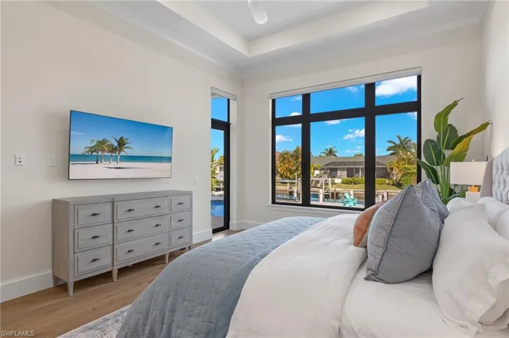Bedroom with access to outside, wood finished floors, baseboards, and a tray ceiling