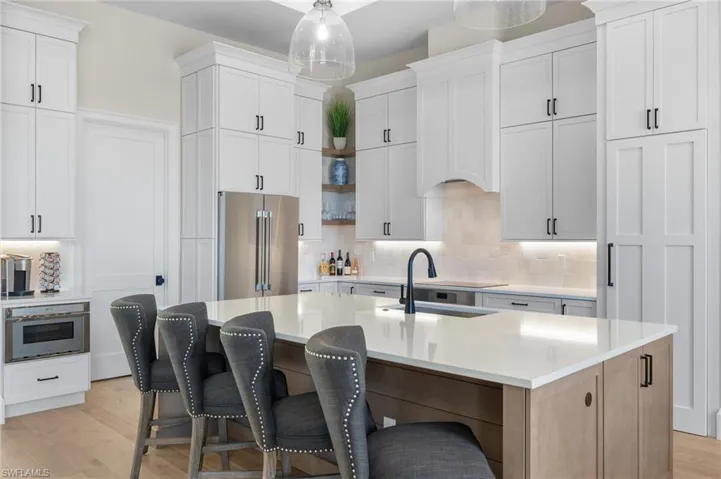 Kitchen featuring appliances with stainless steel finishes, a sink, backsplash, and light wood-style flooring