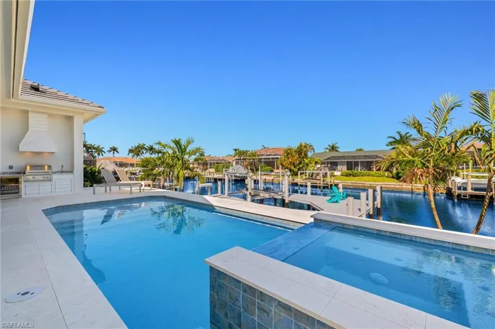 Swimming pool with a dock, a water view, an in-ground hot tub, and boat lift