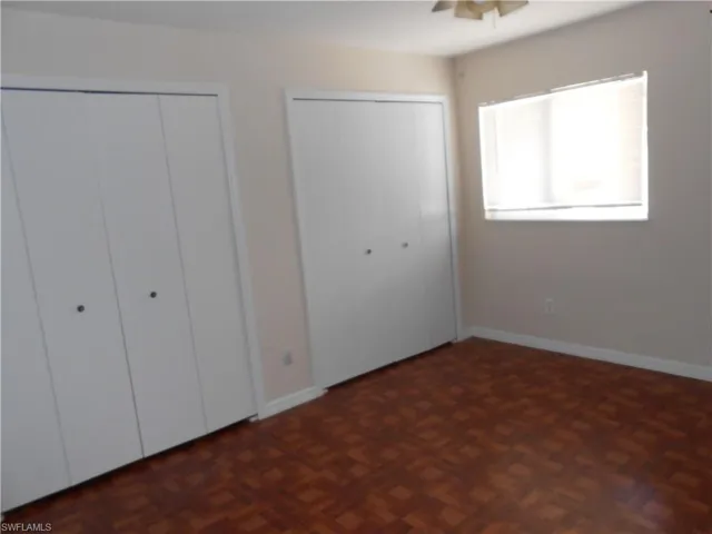 Unfurnished bedroom featuring two closets, parquet flooring, and ceiling fan