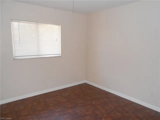 Empty room featuring baseboards and parquet floors
