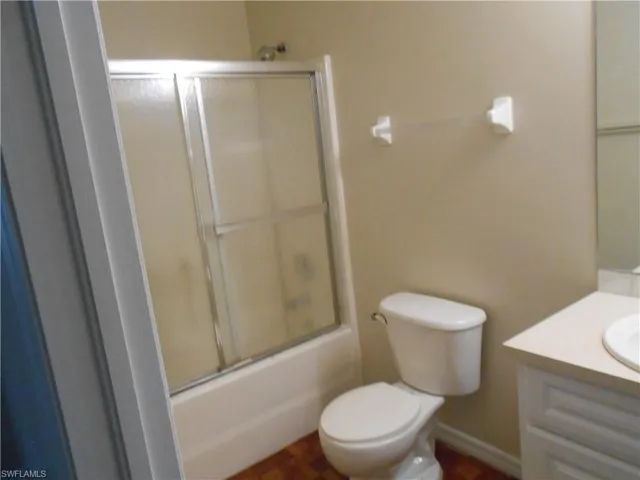 Bathroom featuring vanity and bath / shower combo with glass door