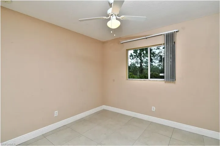 Empty room featuring ceiling fan and light tile patterned flooring