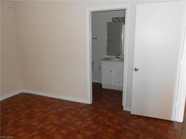 Unfurnished bedroom featuring parquet floors and connected bathroom
