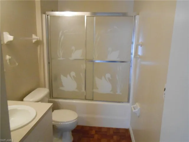Bathroom featuring vanity, combined bath / shower with glass door, and parquet floors