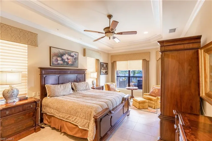 Bedroom featuring crown molding, a raised ceiling, light tile patterned flooring, ceiling fan, and visible vents