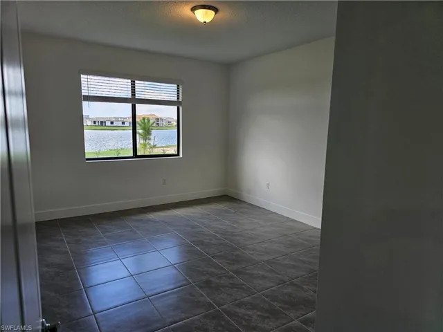 Spare room featuring a water view, dark tile patterned flooring, and a textured ceiling