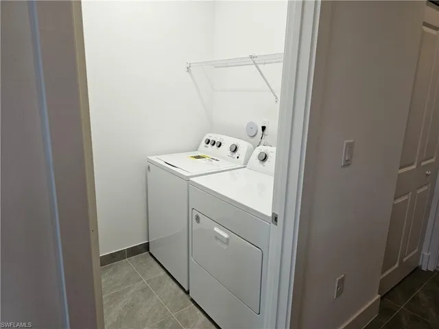 Laundry room with dark tile patterned flooring and washer and dryer