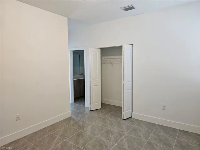 Unfurnished bedroom with a closet, light tile patterned flooring, and a textured ceiling