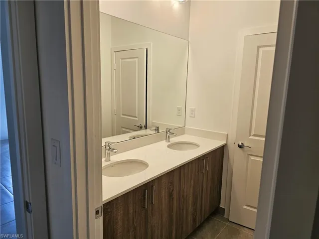 Bathroom with dark tile patterned flooring and double vanity