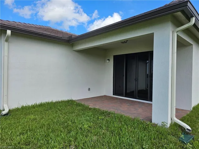 Property entrance featuring a patio, a yard, and stucco siding