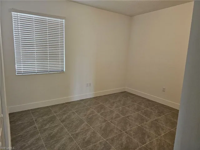 Empty room with dark tile patterned flooring and a textured ceiling