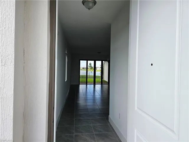 Corridor featuring dark tile patterned flooring, a water view, and a textured wall