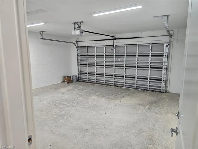 Garage featuring concrete block wall and a garage door opener
