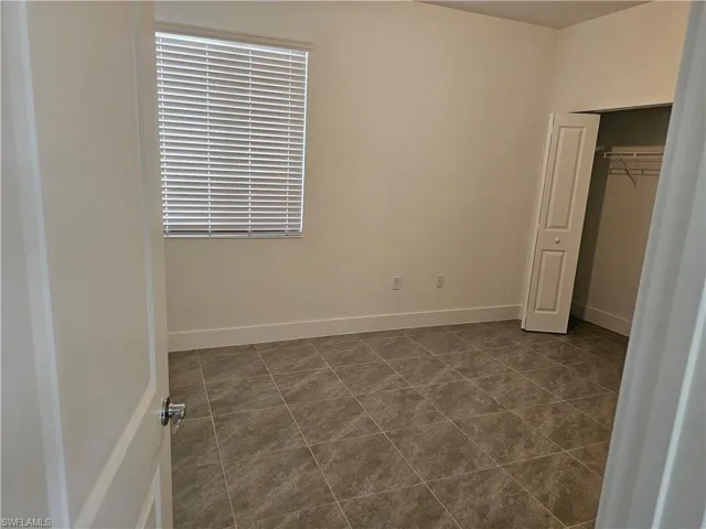 Unfurnished bedroom featuring a closet and dark tile patterned flooring