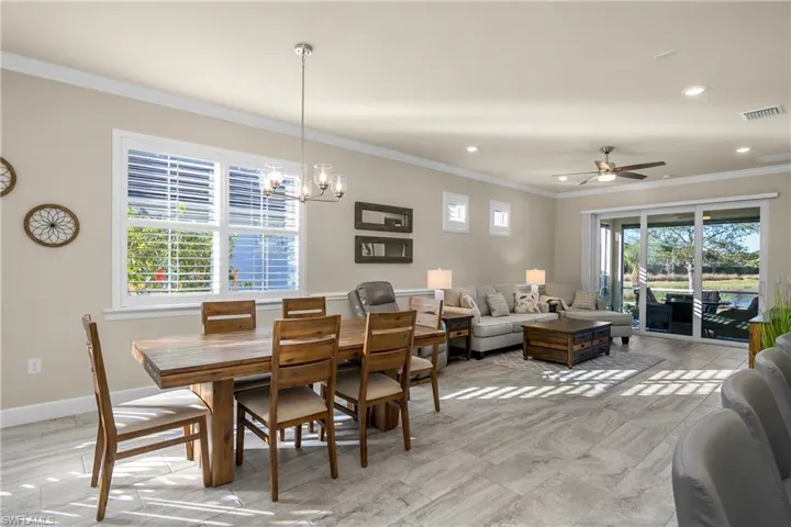 Dining area featuring crown molding, lake view, plenty of natural light, and ceiling fan with notable chandelier