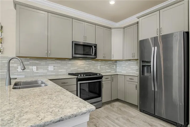 Kitchen with quartz countertops, tile backsplash, crown molding, stainless steel appliances