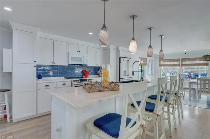Kitchen featuring a breakfast bar, crown molding, light wood-style floors, an island with sink, and white cabinetry
