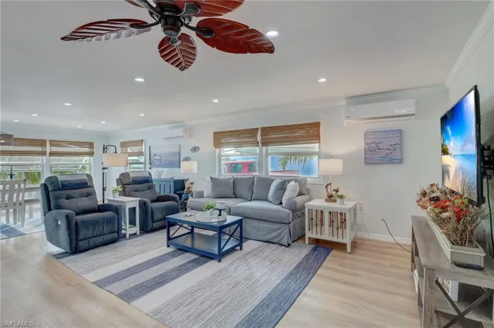 Living area with ornamental molding, a ceiling fan, light wood-style flooring, and recessed lighting