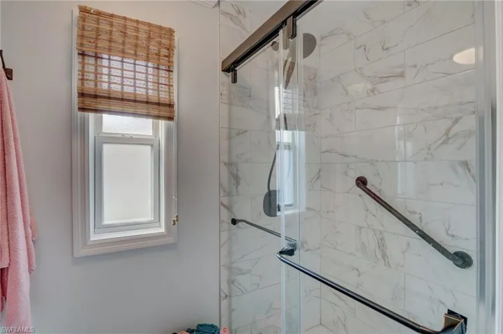 Full bath with a marble finish shower