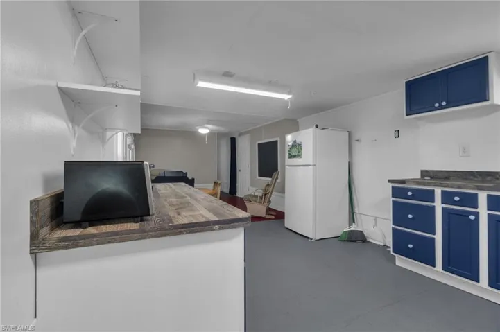 Kitchen with blue cabinetry, open shelves, butcher block counters, and freestanding refrigerator