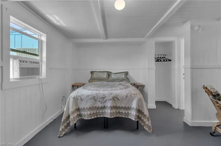 Bedroom with wood floors, cooling unit, and beam ceiling