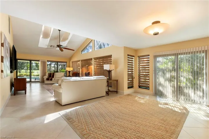 Living area featuring vaulted ceiling, ceiling fan, and light tile patterned flooring