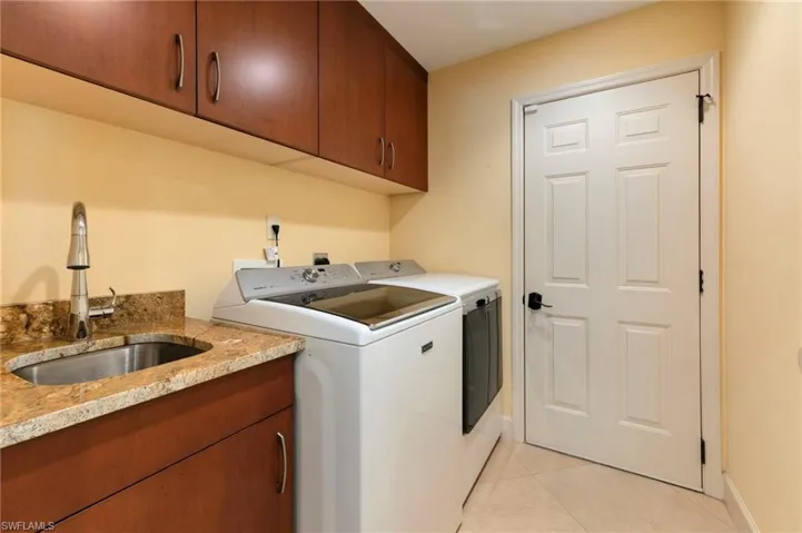 Laundry room featuring light tile patterned floors, washing machine and dryer, and cabinet space