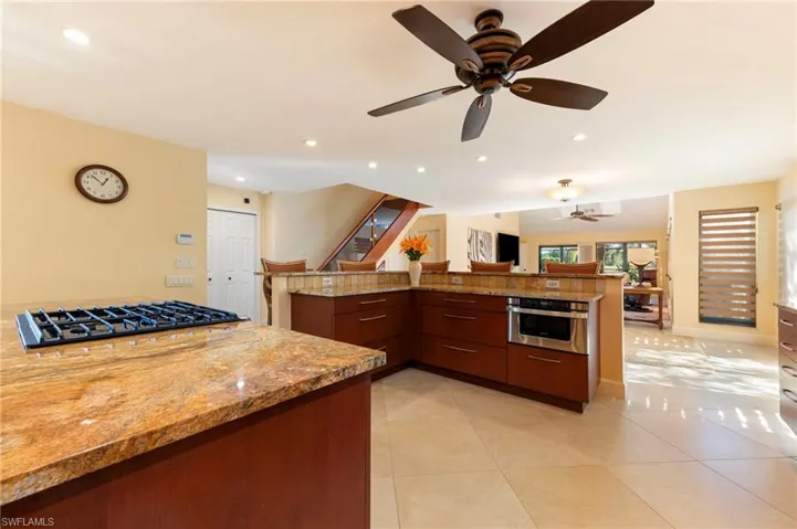 Kitchen featuring open floor plan, oven, modern cabinets, light stone counters, and recessed lighting