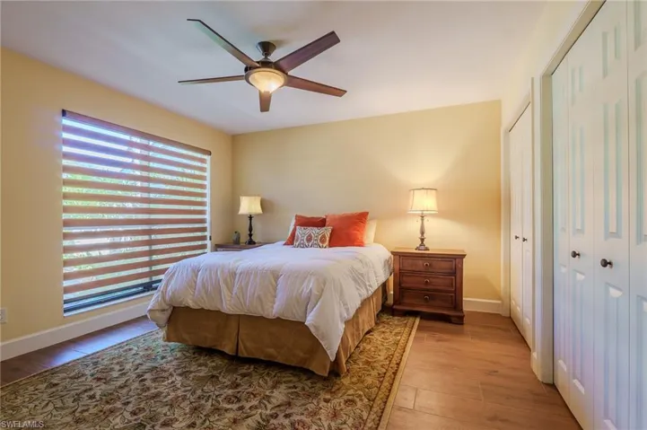 Bedroom with wood-type flooring, a ceiling fan, and multiple closets
