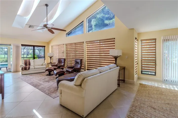Living room with light tile patterned flooring, ceiling fan, plenty of natural light, and vaulted ceiling
