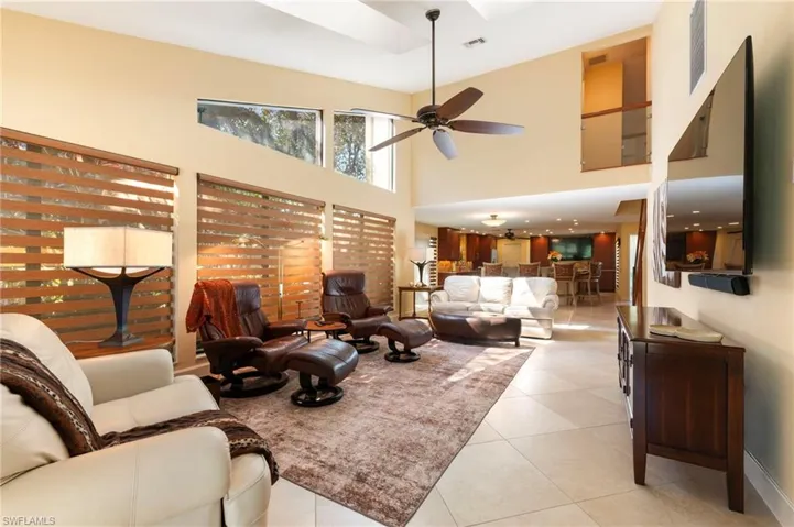 Living room with a high ceiling, light tile patterned flooring, and a ceiling fan