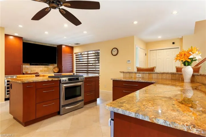 Kitchen featuring gas range, light stone countertops, a kitchen island, ceiling fan, and backsplash