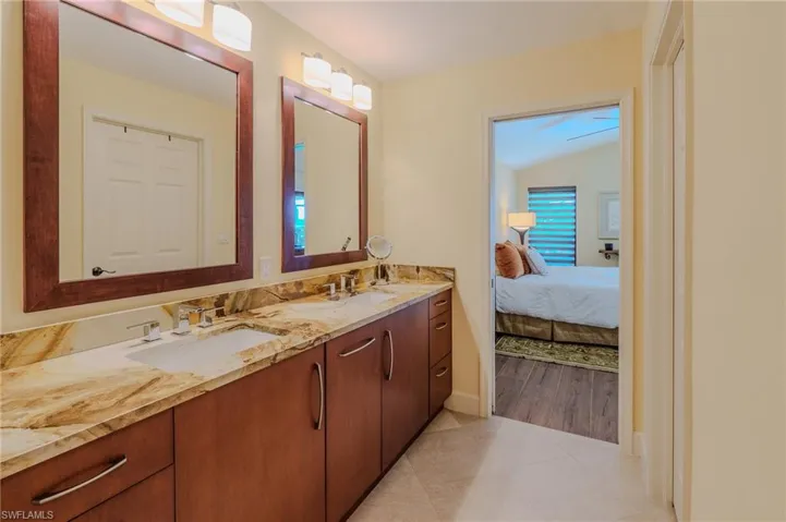 Full bathroom with double vanity, light tile patterned floors, connected bathroom, and lofted ceiling
