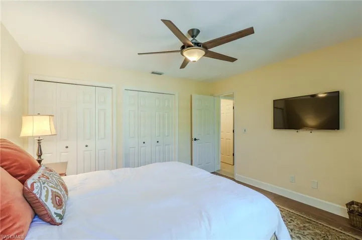 Bedroom featuring two closets, wood finished floors, and a ceiling fan