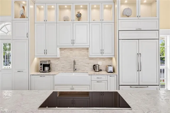Kitchen with healthy amount of natural light, black electric cooktop, light stone countertops, and white cabinets