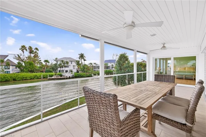 Sunroom featuring a water view, ceiling fan, and outdoor dining space