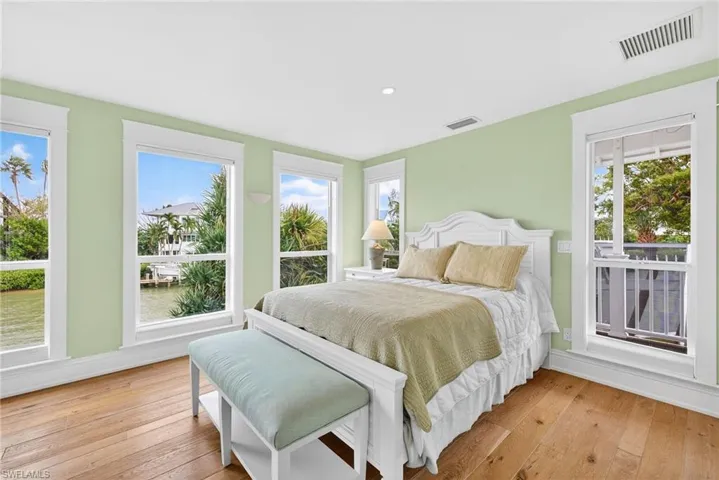 Bedroom with light wood-style floors, a water view, and multiple windows